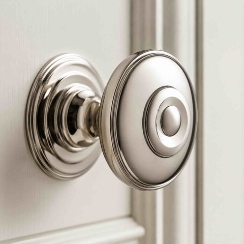 Close-up of 38mm polished nickel round reeded cupboard knob with decorative rose fitted to a light painted cabinet door.