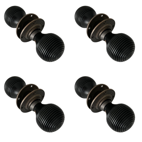 Set of four pairs of ebonised and matt antique beehive door knobs arranged on a white background