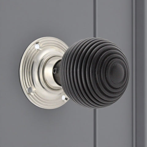 Ebonised wooden beehive door knob with polished nickel backplate fitted to a grey door