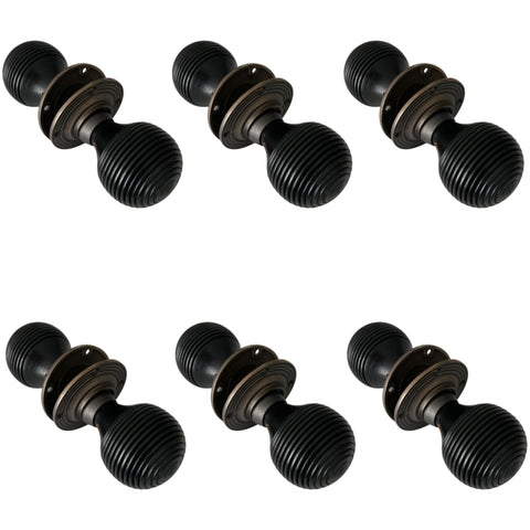 Set of six pairs of black ebonised beehive door knobs with matt antique backplates arranged on a white background.