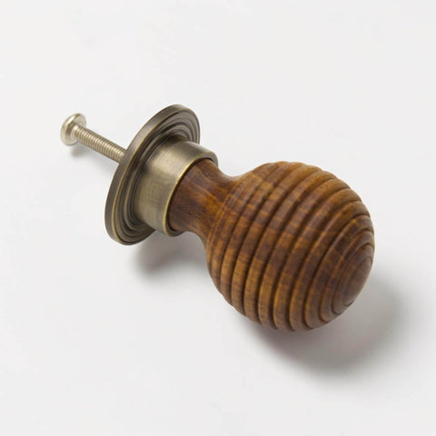 Angled view of large rosewood beehive cupboard knob with antique brass backplate and fixing bolt