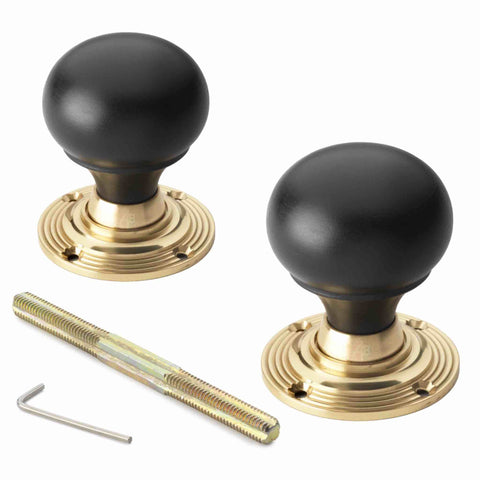 Pair of ebonised black wood bun rim mortice door knobs with unlacquered polished brass backplates, threaded spindle and Allen key.