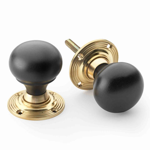 Ebonised black wood bun door knob pair with unlacquered polished brass backplates shown from different angles on a white background.