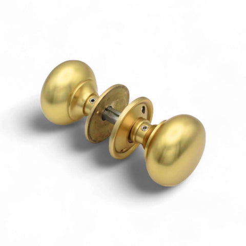Lacquered matt brass cottage door knobs fitted together showing removable backplates and spindle assembly