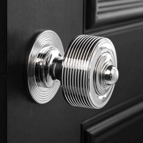 Close-up of a polished chrome reeded centre door knob on a black painted door