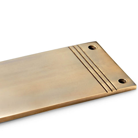 Close-up of reeded detailing on solid brass push plate in unlacquered aged brass with countersunk fixing holes