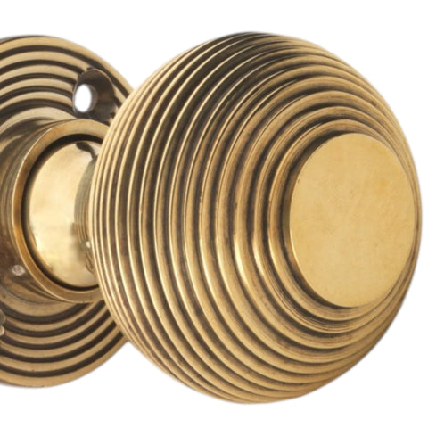 Close-up detail of aged brass reeded beehive door knob showing textured concentric ring design and antique finish