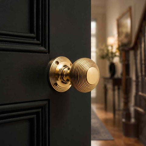 Aged Brass Beehive Mortice Door Knob Pair fitted to a black panelled door in a traditional hallway setting