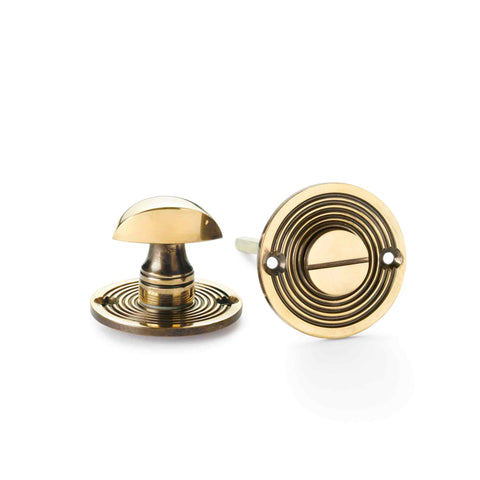 Aged brass beehive thumb turn on white background.