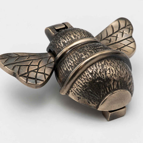 Aged brass bumble bee door knocker shown closed with decorative wing and body detailing