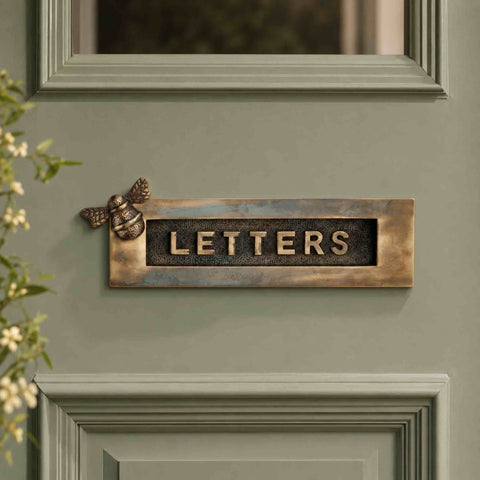 Aged brass bumble bee “LETTERS” letter plate fitted to a sage green front door.