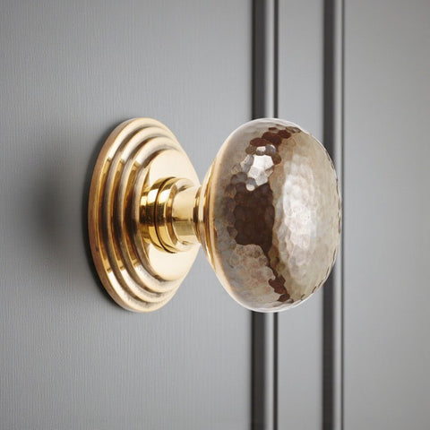 Unlacquered aged brass hammered cottage centre door knob with stepped backplate fitted to painted door