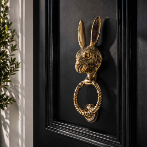 Close-up of aged brass hare door knocker showing detailed hare head, ears and textured finish.