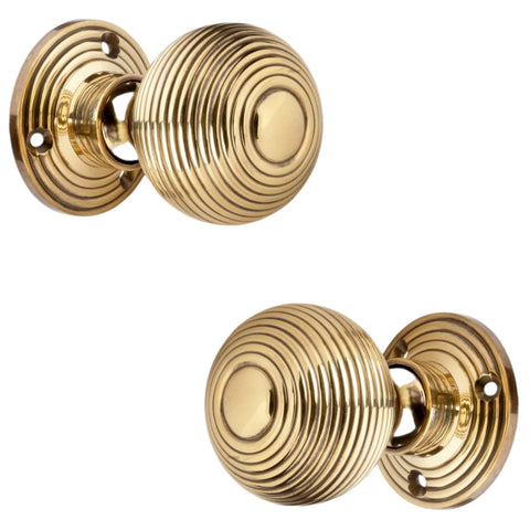 Angled side view of aged brass hollow beehive mortice door knobs showing reeded design and circular backplates