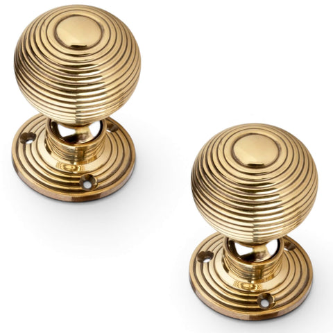 Top angled view of pair of aged brass hollow beehive mortice door knobs on white background