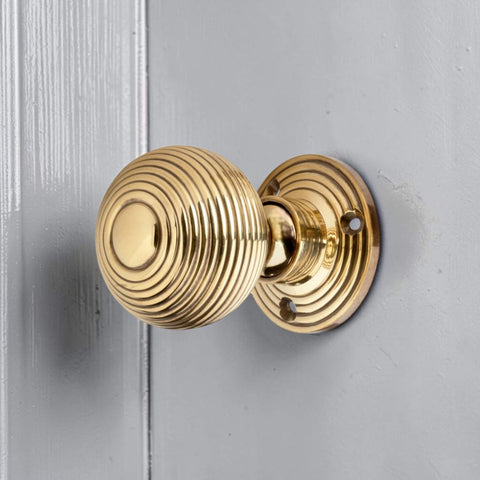 Aged brass hollow beehive mortice door knob fitted to painted grey wooden door
