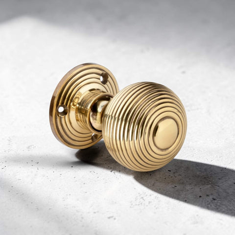 Close-up angled view of aged brass hollow beehive mortice door knob on light stone background