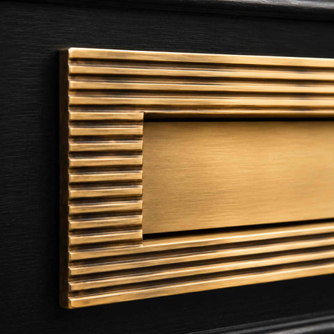 Detailed view of reeded frame and plain flap on solid brass aged brass letter box plate