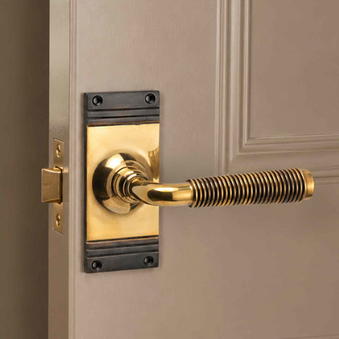 Aged brass reeded lever handle fitted to an internal door with traditional rectangular backplate
