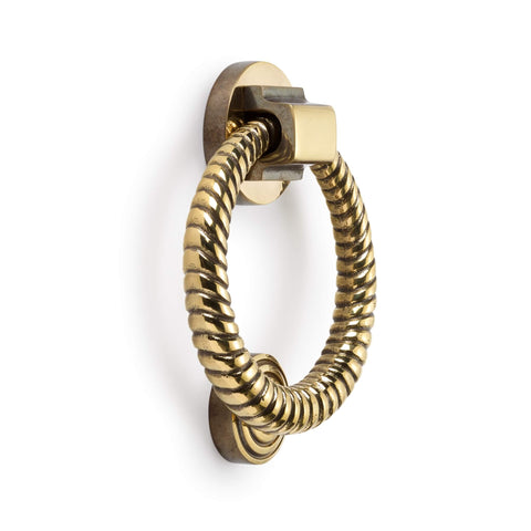 Aged brass reeded ring door knocker angled side view on white background
