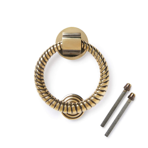 Aged brass reeded ring door knocker with fixing bolts on white background