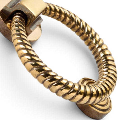 Close-up detail of aged brass reeded ring door knocker showing textured finish