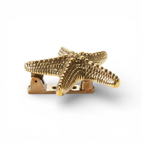 Side view of unlacquered aged brass starfish door knocker showing hinge mechanism and striker mount