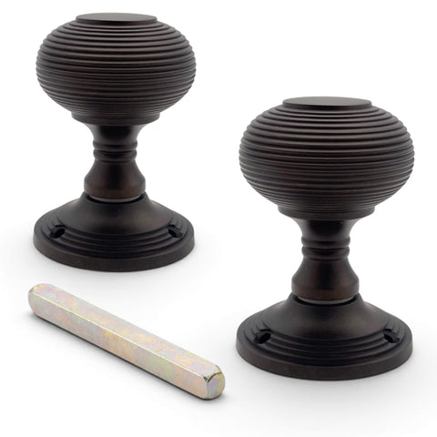 Pair of aged bronze beehive mortice door knobs with spindle and concealed fixing roses