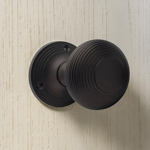 Close-up of aged bronze beehive mortice door knob fitted to textured door surface