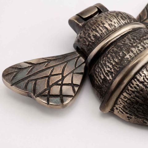 Detailed view of aged brass bumble bee door knocker highlighting textured cast brass body