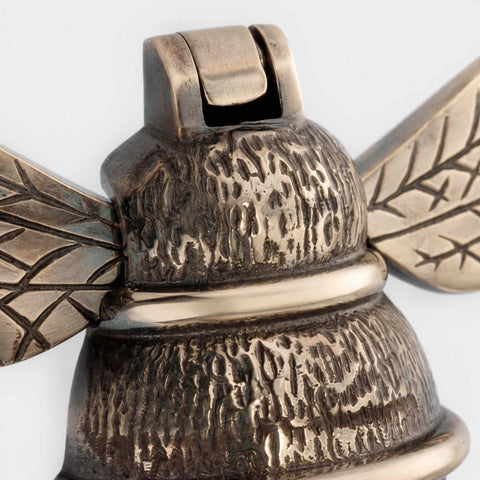 Macro shot of aged brass bumble bee door knocker showing aged finish and hinge detail