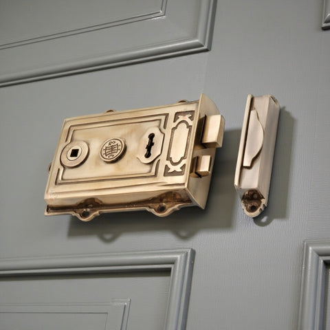 Angled view of aged brass Davenport rim lock installed on a painted door, showing decorative detailing and latch.