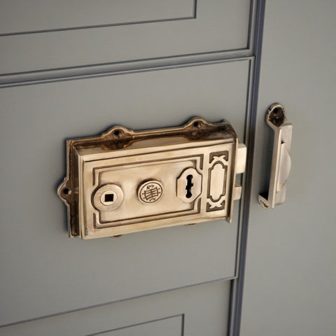 Close-up of aged solid brass Davenport Victorian rim lock and keep fitted to a traditional panel door.