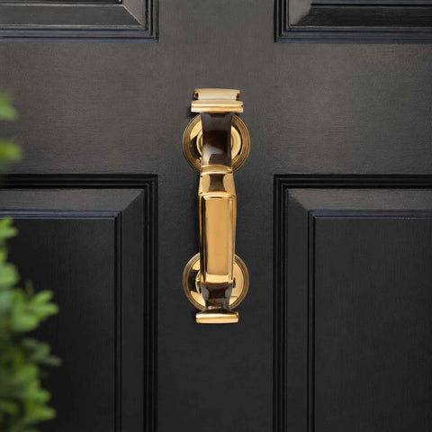 Aged Brass Reeded Doctor Door Knocker mounted on a black front door, featuring a solid brass construction, decorative reeded roses and traditional doctor's knocker design.