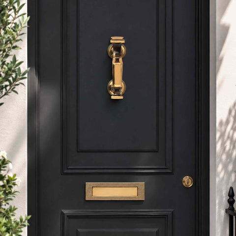 Full entrance view featuring an Aged Brass Reeded Doctor Door Knocker, matching reeded letter plate and key escutcheon on a black front door.