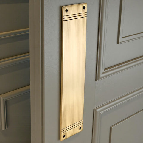 Antique brass reeded push plate fitted to painted door, showing vertical installation and stepped detailing