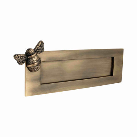 Angled view of antique brass bumble bee letter plate showing plain sprung flap and bee detailing