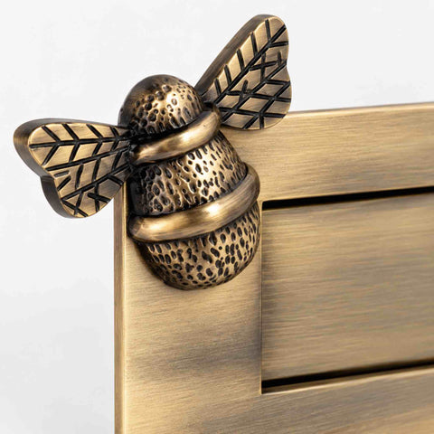 Close-up of decorative bumble bee detailing on antique brass letter plate