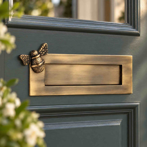 Antique brass bumble bee letter plate fitted to a dark traditional front door