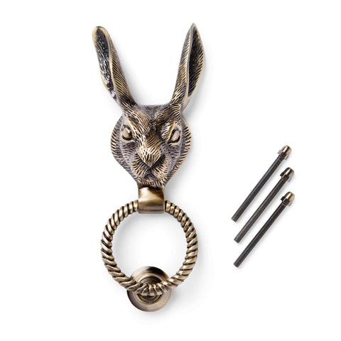 Solid brass antique brass hare door knocker with reeded ring and fixing bolts on a white background.