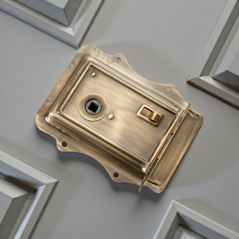 Antique brass Victorian rim lock fitted to painted timber door showing traditional proportions