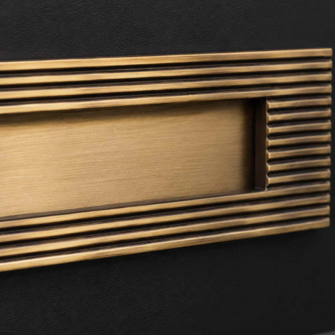 Close-up of antique brass reeded frame and plain sprung flap letter box plate