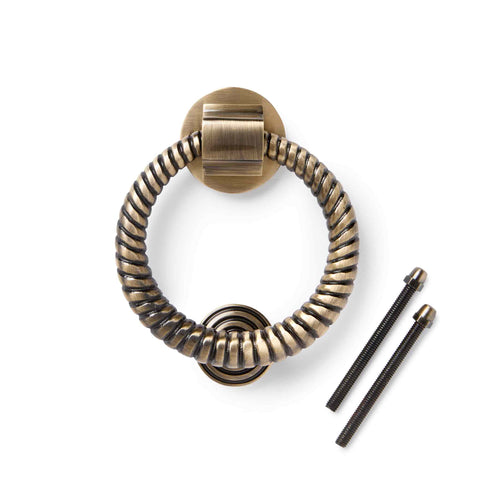 Antique brass reeded ring door knocker with supplied fixing bolts on a white background