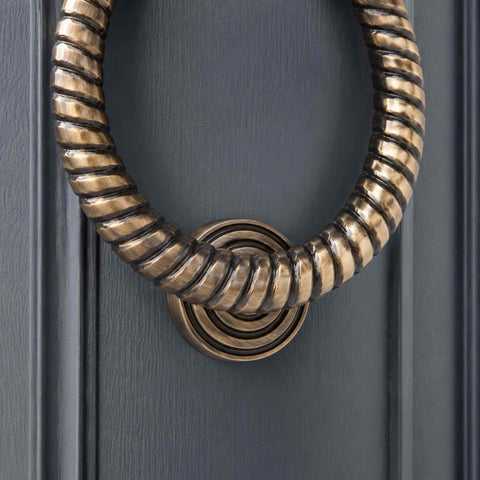 Close-up of antique brass reeded ring door knocker showing detailed spiral ring design