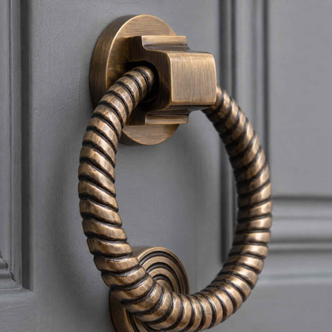 Antique brass reeded ring door knocker fitted to a traditional dark entrance door