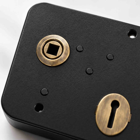 Close-up of black and antique brass left hand Scotch rim lock showing keyhole escutcheon and handle follower