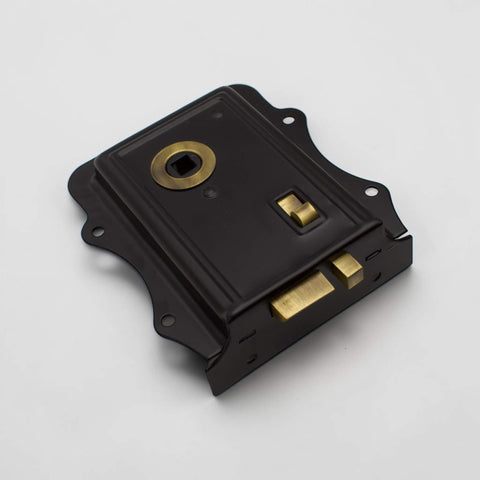 Black and antique brass Victorian rim lock shown from an angled front view with antique brass latch and spindle surround.