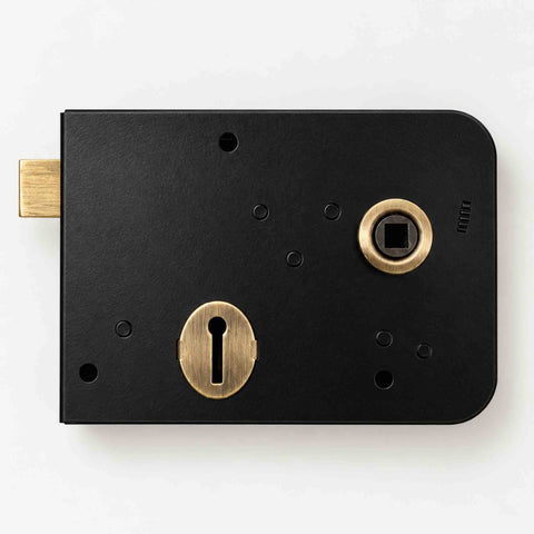 Front view of black and antique brass right hand Scotch rim lock showing latch, keyhole and handle follower