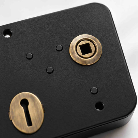 Close-up of black Scotch rim lock showing antique brass keyhole escutcheon and square handle follower