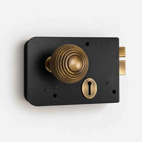 Close-up of black and antique brass Scotch rim lock with traditional reeded beehive door knob